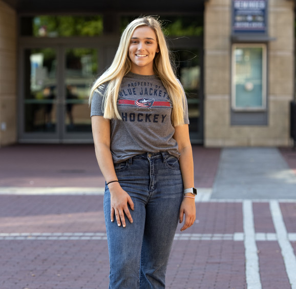 Woman smiling while wearing Columbus Blue Jacket gear